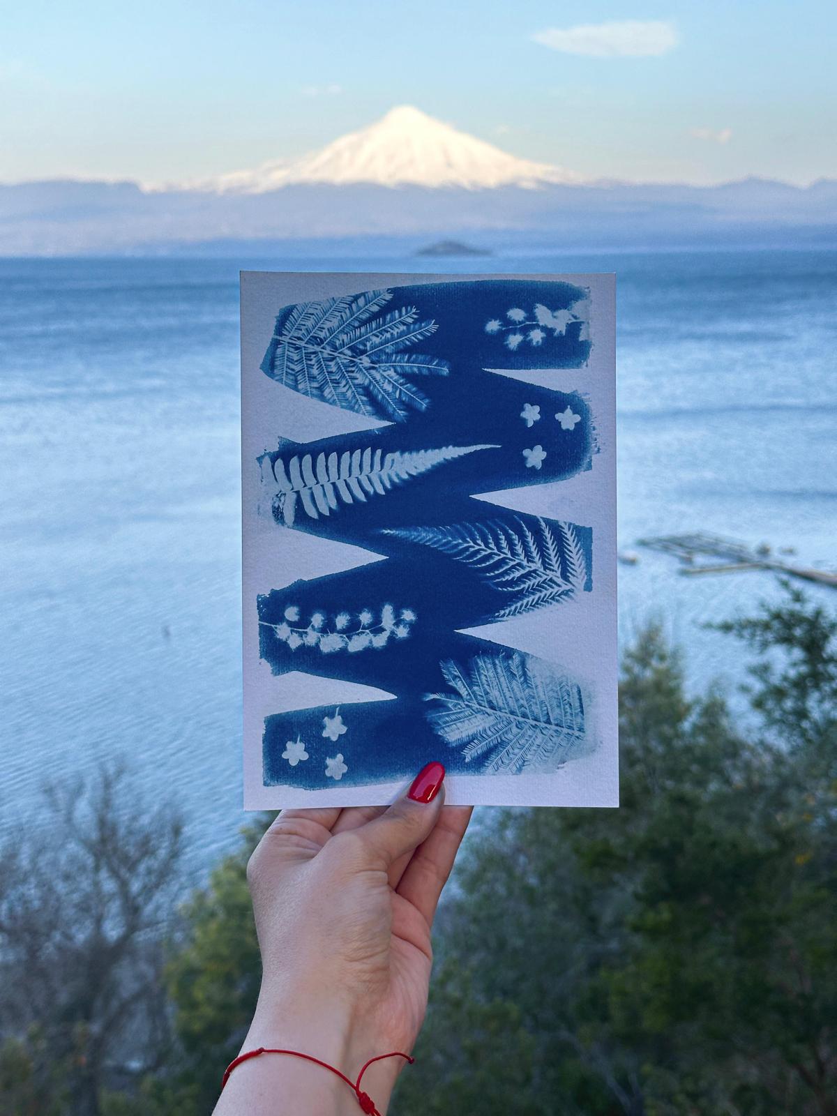 Cyanotype met zigzagpatroon en bloemen, achtergrond toont meer met vulkaan